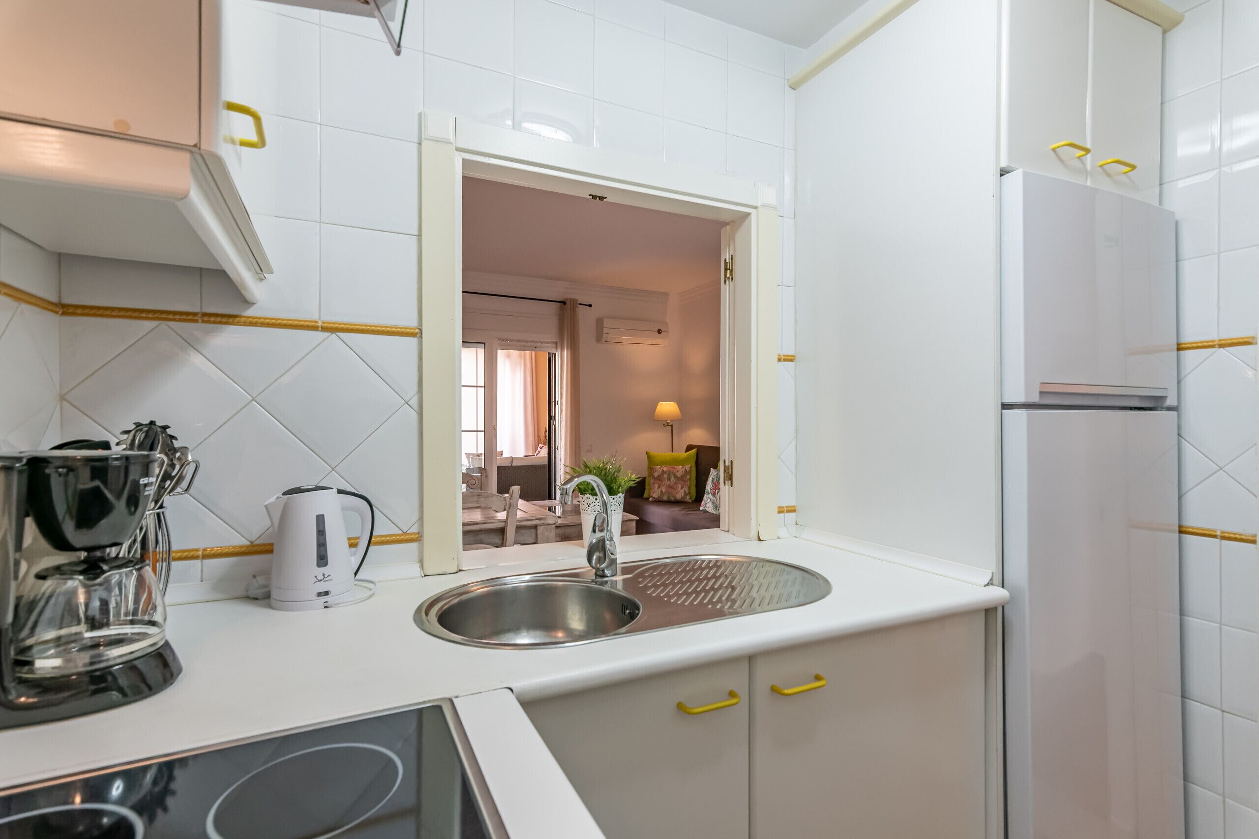A modern kitchen with a sink, a coffee maker, and a refrigerator.