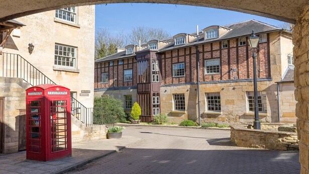 A traditional building with a red telephone booth, stone walls, and a paved courtyard. - A sudeley castle cottage that sleeps 4 guests  in 2 bedrooms (Cheltenham)