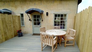 A wooden deck with a round table and four chairs, a door labeled "George III", and a wooden fence. - A sudeley castle cottage that sleeps 4 guests  in 2 bedrooms (Cheltenham)