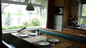 A kitchen with a dining area, a microwave, a refrigerator, and a window with a view of greenery.