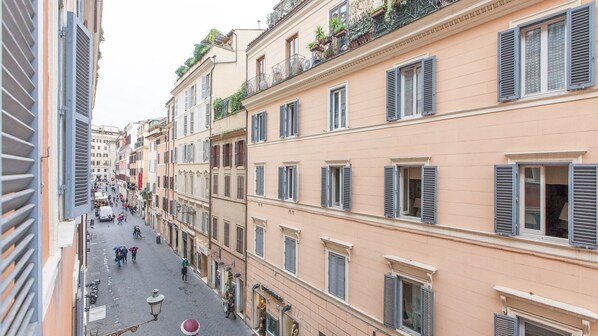 A narrow street lined with multi-story buildings, each with shutters and balconies. - Frattina Exclusive Apartment (Rome)