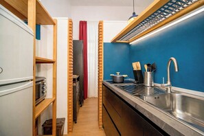 Une cuisine étroite, dotée d’une cuisinière encastrée, d’un évier avec un robinet moderne et d’une casserole posée sur le plan de travail.