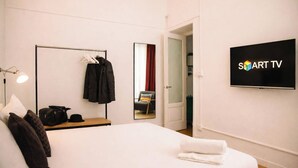 A hotel room with a bed, a TV, a mirror, a coat rack, and a door leading to another room. - Nilo's Flat - Location in the historic center of Naples  (Napoli)