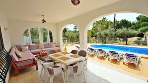 A sunlit outdoor living area with a pool, a sofa, a dining table, and lounge chairs. - Albertina - pool & garden, close to beach (Benissa)