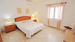 A bedroom with a bed, bedside lamps, a chair, a radiator, and two wall-mounted pictures. - Albertina - pool & garden, close to beach (Benissa)