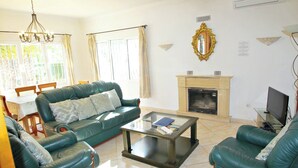 A living room with a green sofa set, a glass coffee table, a fireplace, and a television. - Albertina - pool & garden, close to beach (Benissa)