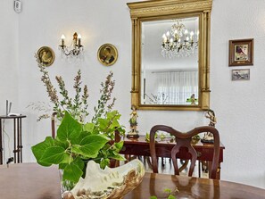 Zona de dinar amb taula, cadira, llum d'estuc, quadres penjats i un mirall.
