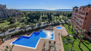 A hotel with a large swimming pool, palm trees, and a view of the sea. - Playa Verde - Punta del Moral Beach PPHV31P26 (Punta del Moral)