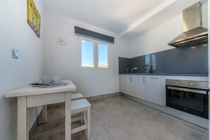 A modern kitchen with a built-in oven, a window, and a small dining area with a table and chairs.