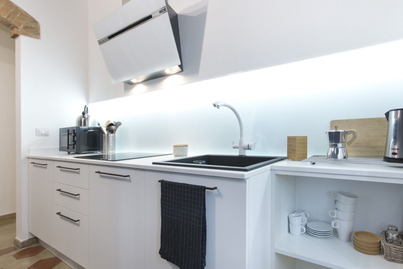 Eine moderne Küche mit weißen Schränken, einer schwarzen Arbeitsplatte, einem Spülbecken und einer Kaffeemaschine.