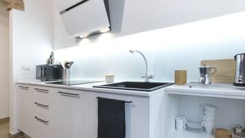 Eine moderne Küche mit weißen Schränken, einer schwarzen Arbeitsplatte, einem Spülbecken und einer Kaffeemaschine.