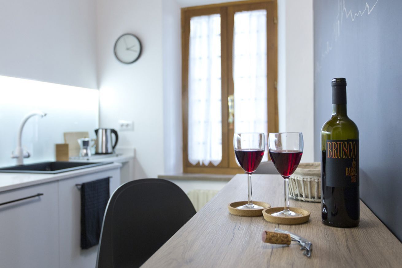 Eine Küche mit einem Holztisch, zwei Gläsern Rotwein, einer Weinflasche und einem Korkenzieher.