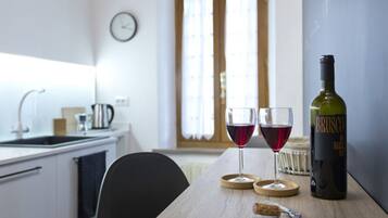 Eine Küche mit einem Holztisch, zwei Gläsern Rotwein, einer Weinflasche und einem Korkenzieher.