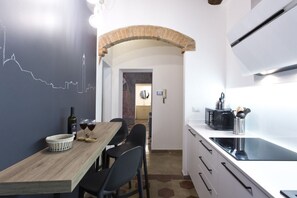 Een moderne keuken met een houten eettafel, zwarte stoelen en een zwart aanrecht.
