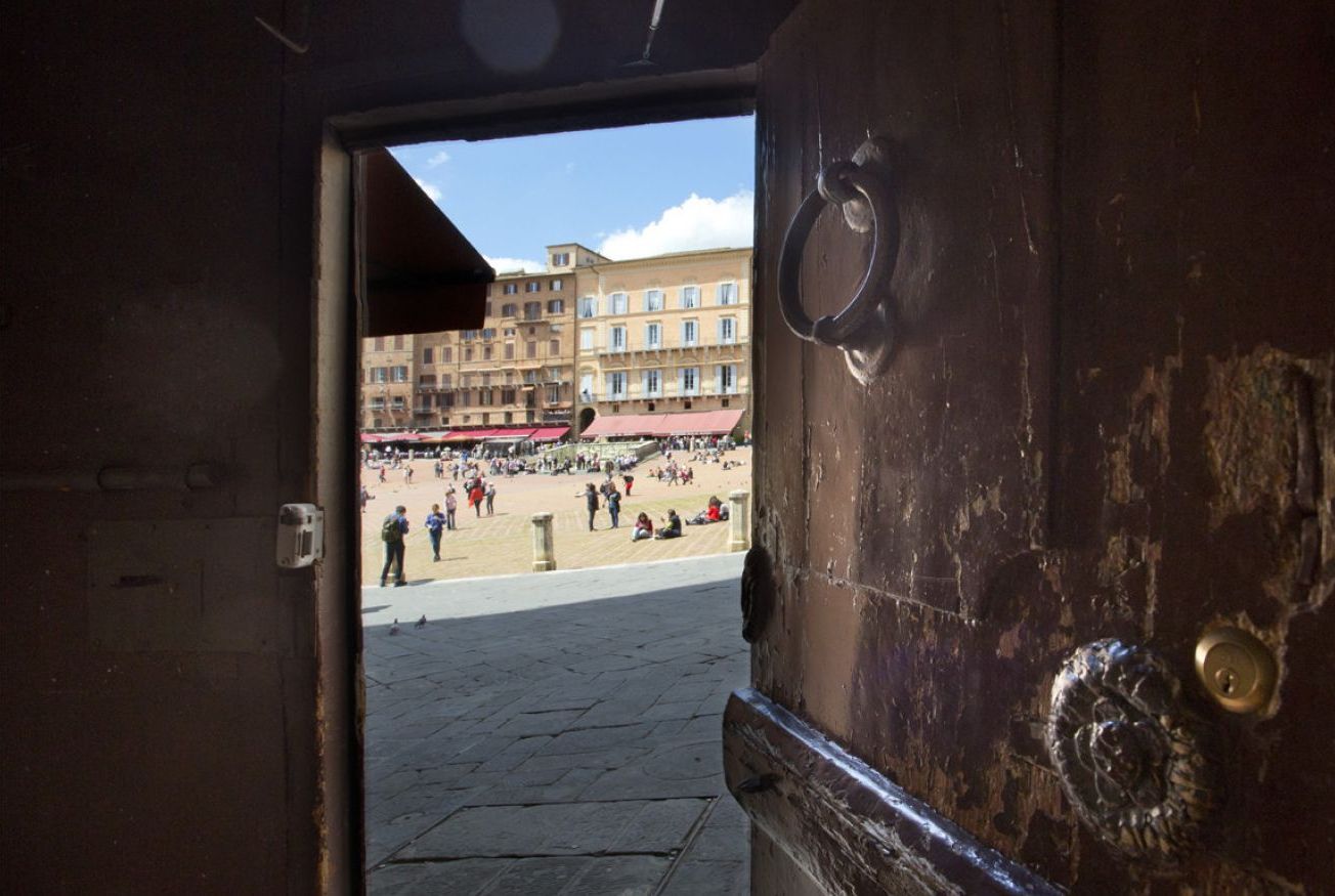An open door leading to a public square with buildings in the background.