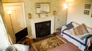 Una habitación acogedora con chimenea, una cama con colcha, televisor y lámpara.