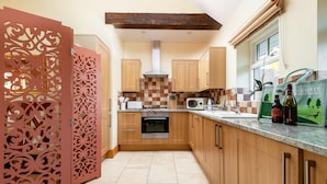 Una cocina moderna con armarios de madera, horno empotrado y microondas.