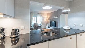 Une cuisine moderne avec un plan de travail noir, des appareils en acier inoxydable et des luminaires suspendus.
