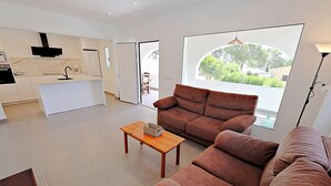 Un salon moderne avec un canapé marron, une table basse en bois et une grande fenêtre donnant sur un paysage verdoyant.