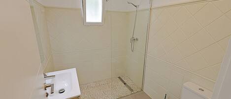 A bathroom with a shower, toilet, and sink.