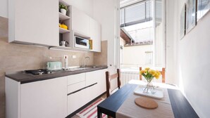 Una cucina moderna con mobili bianchi, un piano di lavoro nero e una finestra che lascia entrare luce naturale.