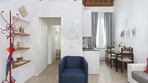 Un soggiorno moderno con una poltrona blu, un tavolo da pranzo in legno e un angolo cottura.