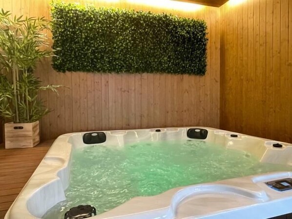 Een hottub met groen water, omgeven door houten wanden en een groene wanddecoratie.