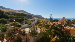 Une vue sur la côte, avec un ciel dégagé, une montagne en arrière-plan et un bâtiment doté d’un toit en tuiles.