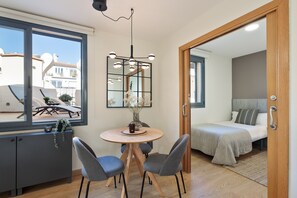 Una habitación compacta con cama, una mesa de comedor y sillas, y un ventanal grande.