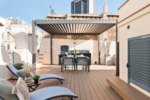 Un patio exterior con zona de comedor cubierta, sillas de lounge y una cocina.