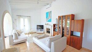 A spacious living room with a white sofa, a TV, and a wooden cabinet. - Golondrina - panoramic hillside holiday house in Moraira (Moraira)