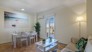 A living room with a dining area, a sofa, a coffee table, and a lamp. - Canela Park Penthouse - Isla Canela Beach ICHP249P183 (Isla Canela)