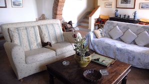 Ein gemütliches Wohnzimmer mit zwei Sofas, einem Holztisch und einer Treppe, die in eine obere Etage führt.