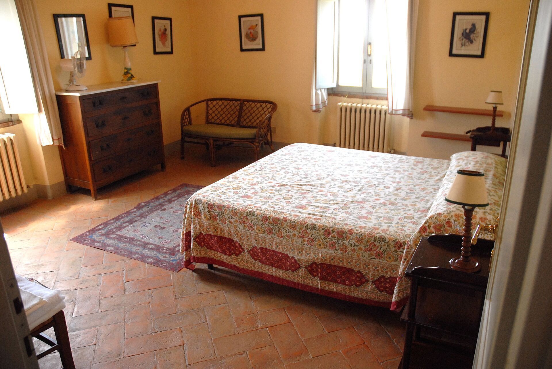 Une chambre à coucher avec un lit, une commode, une chaise et un radiateur.