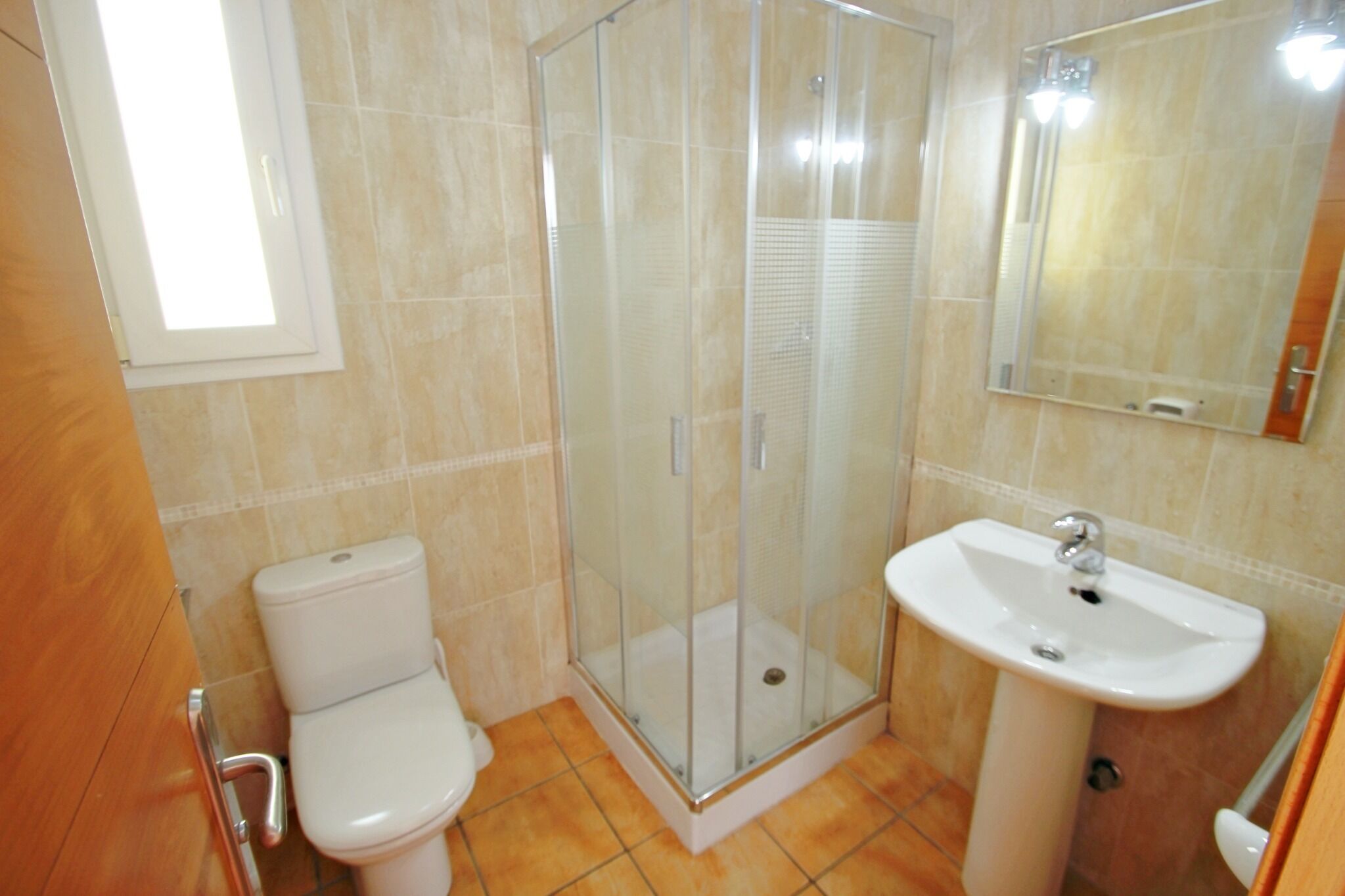 Een badkamer met toilet, een douche met glazen wanden en een wastafel.