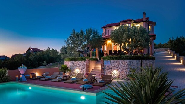 A two-story house with a swimming pool, outdoor seating, and a stone wall. - Luxury Villa Antoneta with Swimming Pool (Šibenik)