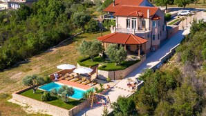 A large house with a swimming pool, surrounded by greenery and a stone wall. - Luxury Villa Antoneta with Swimming Pool (Šibenik)