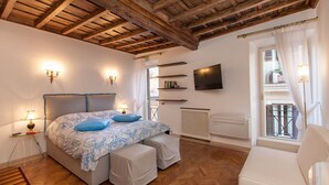 Un dormitorio con cama, lámparas de noche, televisor y balcón con vistas.