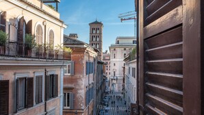 Una calle estrecha con edificios históricos, una torre de campanas y una vista a través de una puerta de madera.
