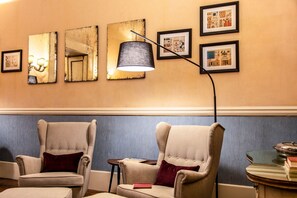 Relax in a stylish space with two armchairs, a floor lamp, and artwork adorning the walls.