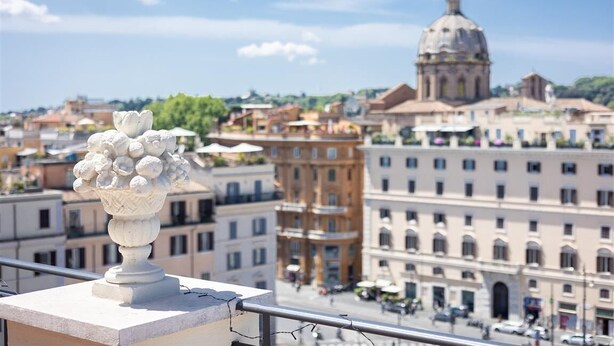 A balcony with a white decorative vase, overlooking a cityscape with historic buildings and a prominent dome structure. - Argentina Penthouse in the heart of the historic center (Rome)