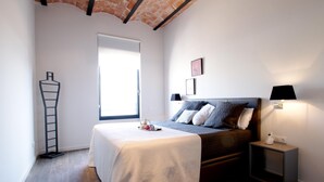 A bedroom with a bed, bedside table, lamp, and a window.