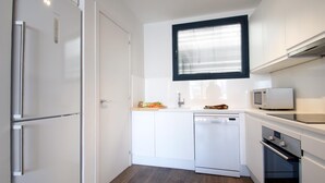 A compact kitchen with white cabinetry, a built-in dishwasher, a microwave, and a stove.