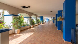Un pasillo con piso de baldosas, paredes azules y plantas en macetas.