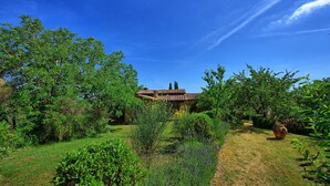 Una villa con techo de tejas, rodeada de abundante vegetación y plantas en flor.