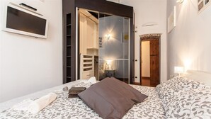 Een slaapkamer met een bed, een kledingkast, een spiegel en een televisietoestel.