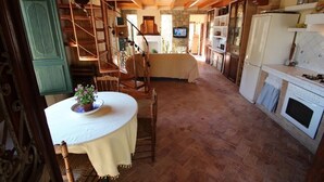 A rustic kitchen with a wooden staircase, a dining table with a potted plant, and a television in the background. - Rocasol - rustic finca for nature lovers in Benissa (Benissa)