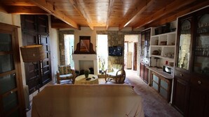 A rustic room with wooden beams, a stone fireplace, a television, and a dining area with a table and chairs. - Rocasol - rustic finca for nature lovers in Benissa (Benissa)