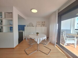 A modern kitchen with white cabinets, a built-in oven, and a dining area with a round table and chairs. - AL 230 - Apartment near the beach (Vera playa)