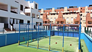 A tennis court with a blue fence and a net, surrounded by buildings with balconies. - AL 230 - Apartment near the beach (Vera playa)
